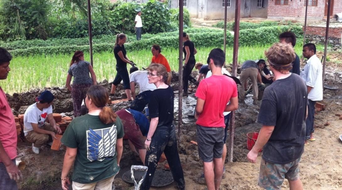 A group of volunteers help to construct a new school for Nepali children during their Building Programme in Nepal. They are digging and laying bricks.