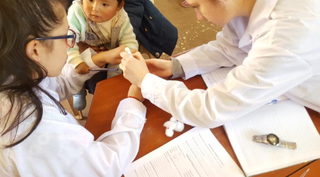 Volunteers check iron levels in a child's blood