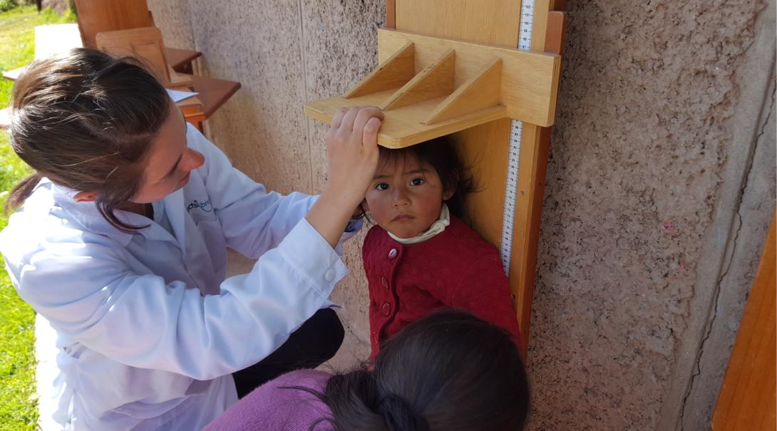 Volunteer measuring the height of a child