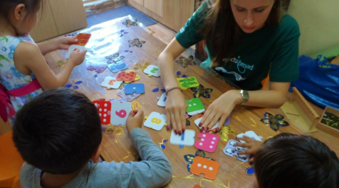 Projects Abroad volunteer working with children in Mongolia helps a group of children with mathematic skills at a care centre.