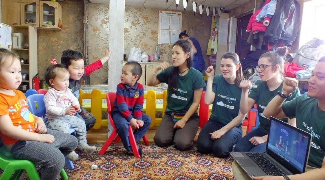 A group of female volunteers working with children in Mongolia demonstrate personal hygiene at a care centre.