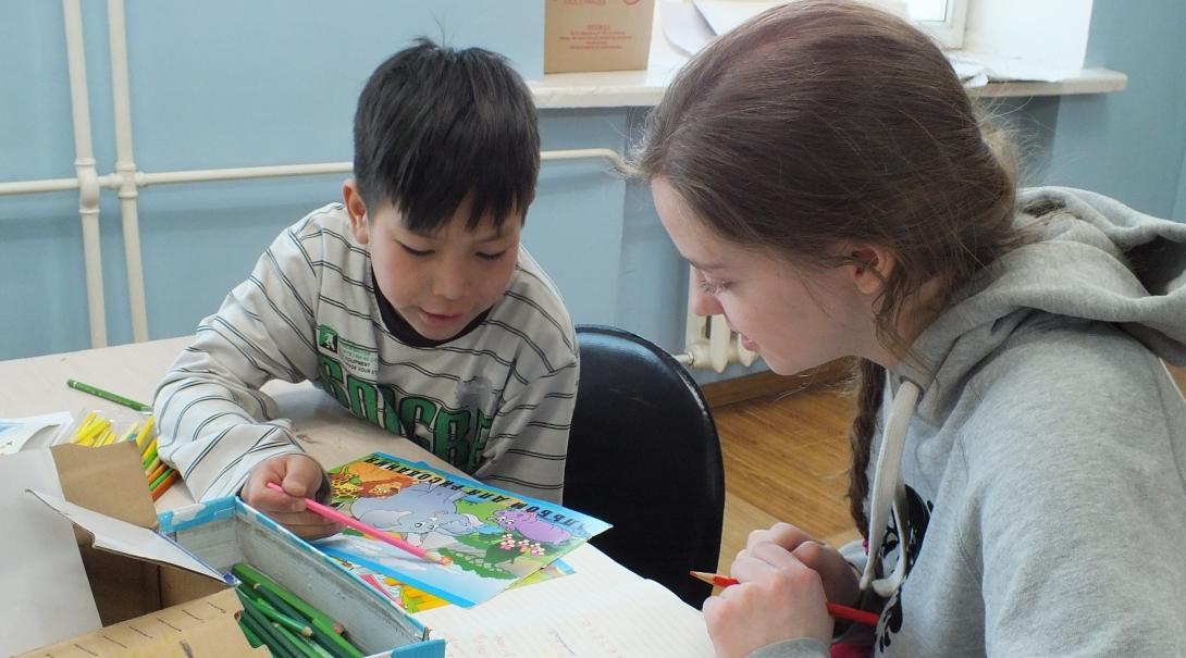 A young child reads to a Projects Abroad volunteer working with children in Mongolia at a local school. 