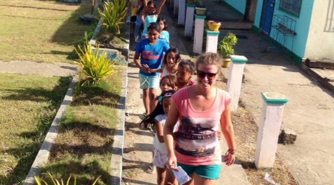 Projects Abroad volunteer working with children in Philippines leads school children outside their kindergarten at her Childcare Project.