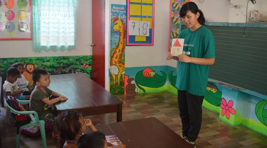 A group of children listen to a class taught by a Childcare volunteer working at a kindergarten in the Philippines. 