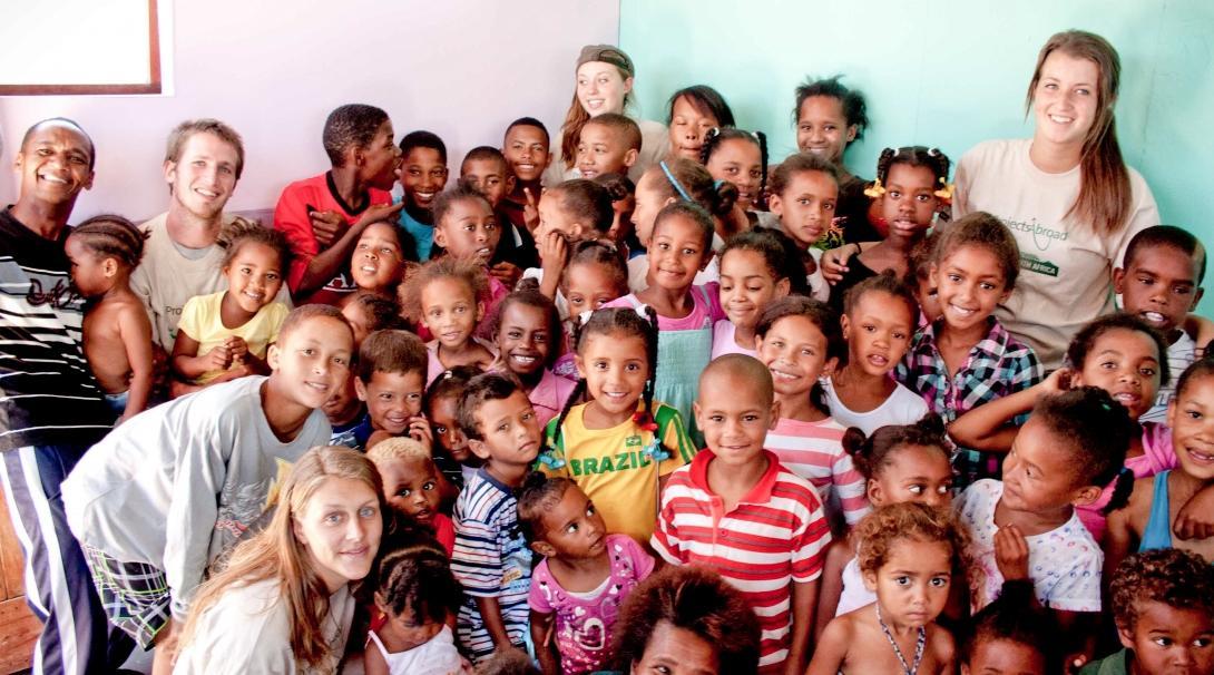 Childcare volunteers with children in South Africa pose for a group photo during a care and community project.