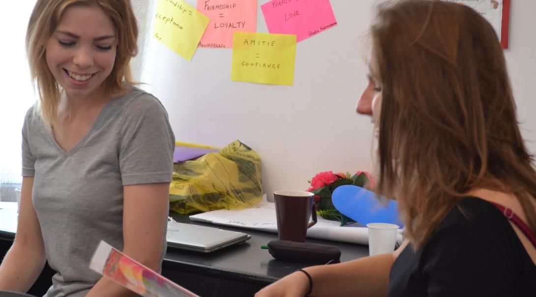 Business Intern sits at a desk with a female staff member of a Cashmere Factory at his placement in Mongolia.