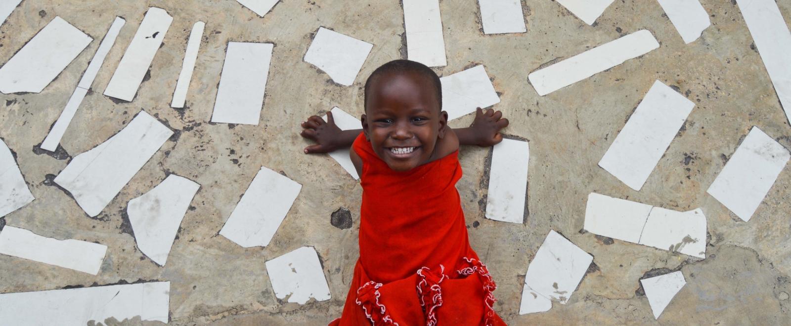 In an project volunteering with children in Tanzania a child smiles outside a care centre.