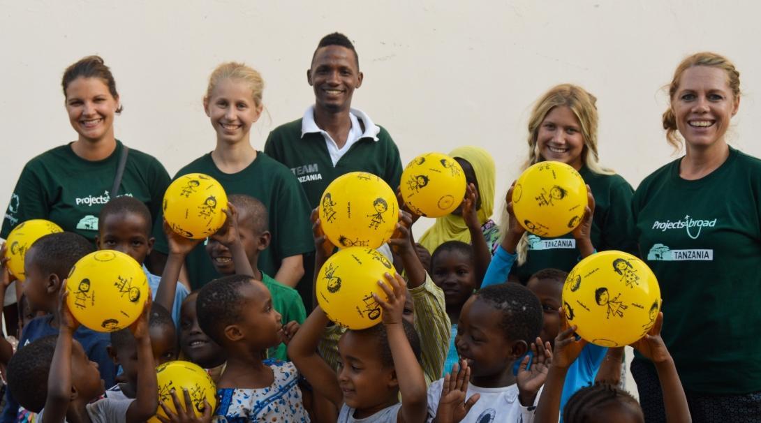 Childcare volunteers working with children in Tanzania pose for a picture with teachers and children during a Care outreach.