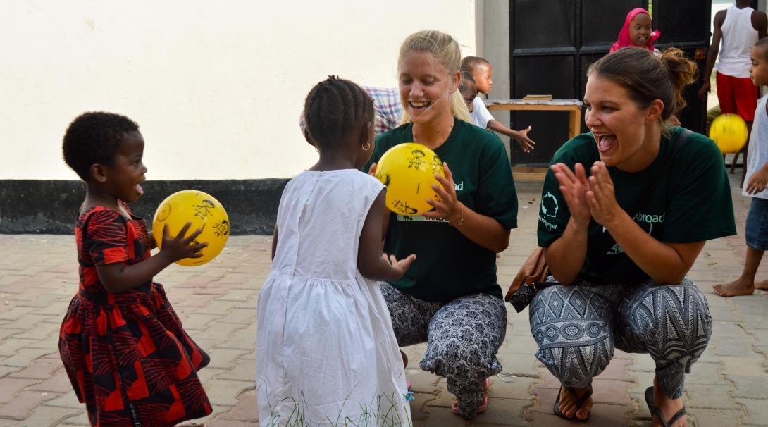 Projects Abroad volunteers with children in Tanzania play ball activities outside a kindergarten.