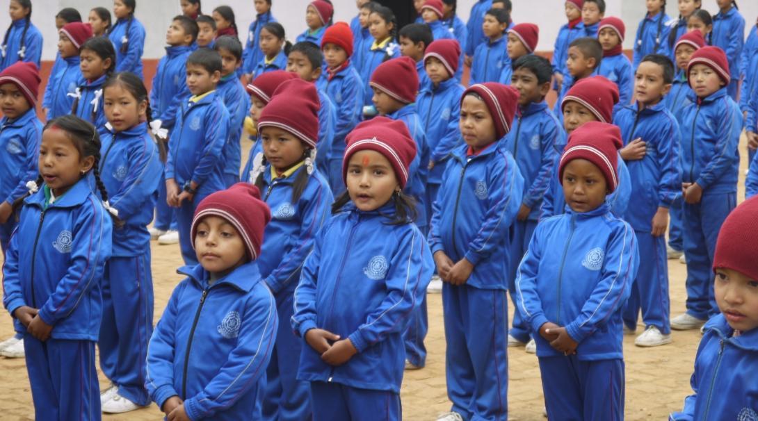 A group of volunteers over 50 doing childcare volunteering in Nepal, work with children during an outdoor activity. 