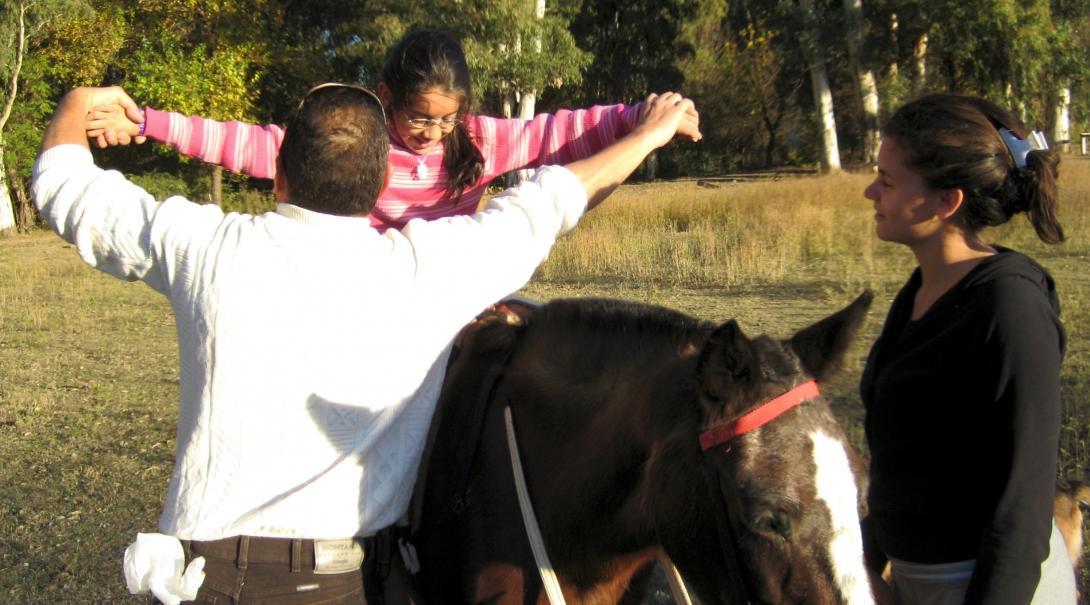 Equine Therapy interns help a young child ride a horse during a therapy session at a centre in Argentina.