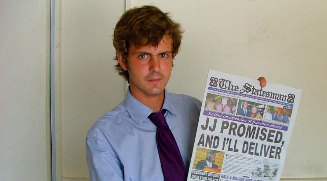 An intern at a journalism placement in Ghana holds up a newspaper