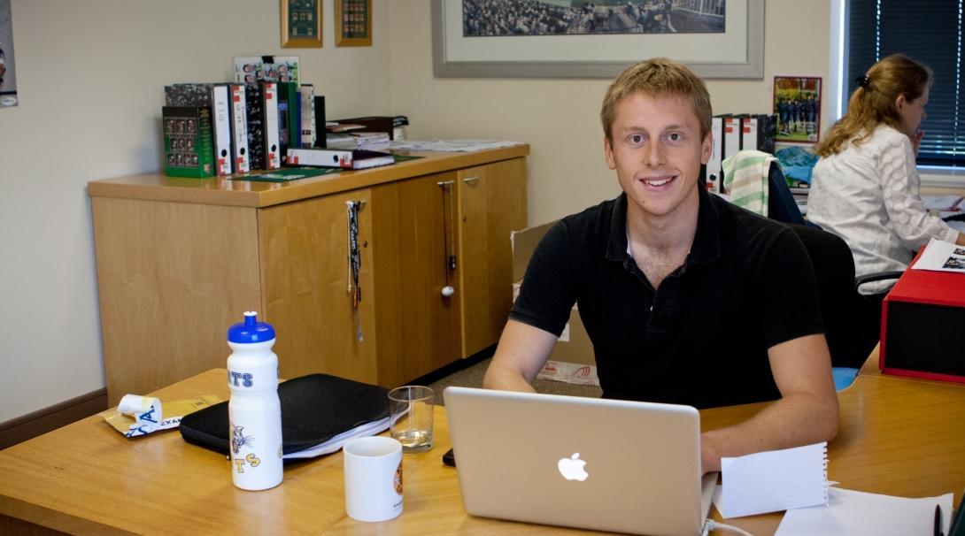 International Development intern works at a computer desk in a business office during internship in South Africa.