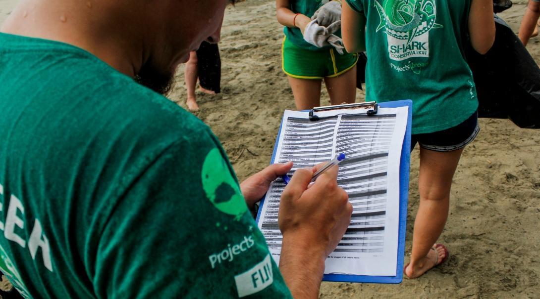 Volunteers from Projects Abroad are seen participating in a beach clean up as part of their shark conservation volunteering work in Fiji.