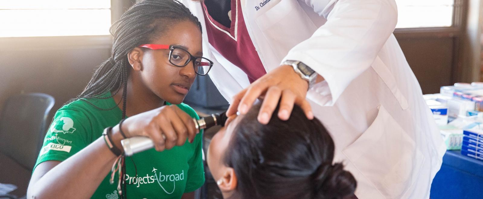 Female Medical intern examines a patient's mouth with a doctor during a Medical Outreach Programe in Mexico.