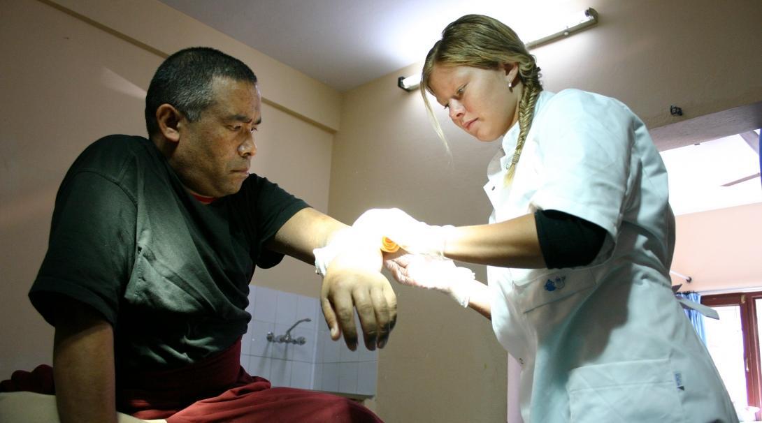 A female Projects Abroad intern is pictured cleaning a patients wound whilst on her medical internship in Nepal.