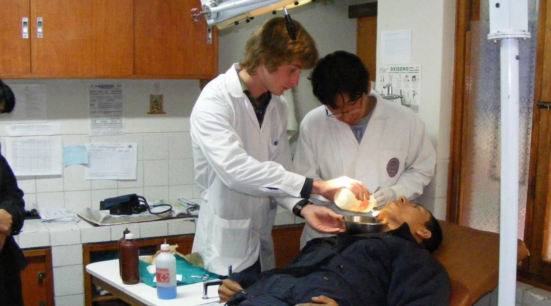 A male intern from Projects Abroad is seen assisting a local doctor in an emergency ward during his medical internship in Peru.