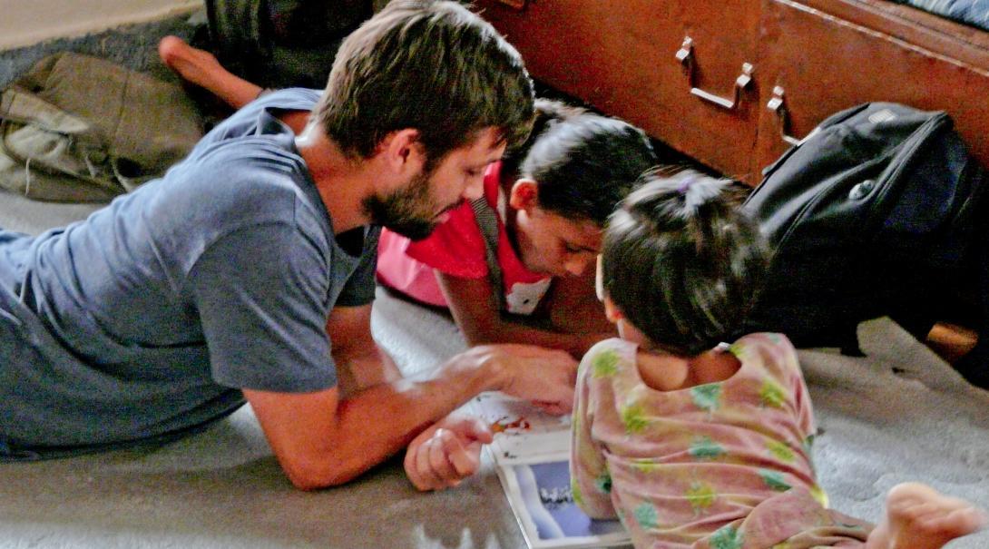 A Projects Abroad volunteer teaching English in Nepal reads a book to his students