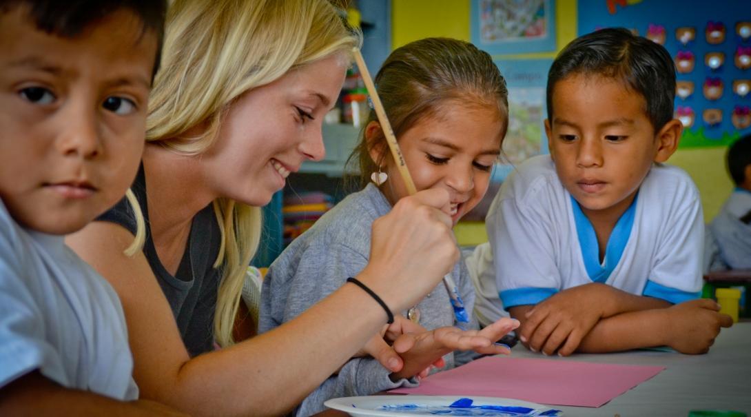 A volunteer teaching in Ecuador helps her students with the arts project