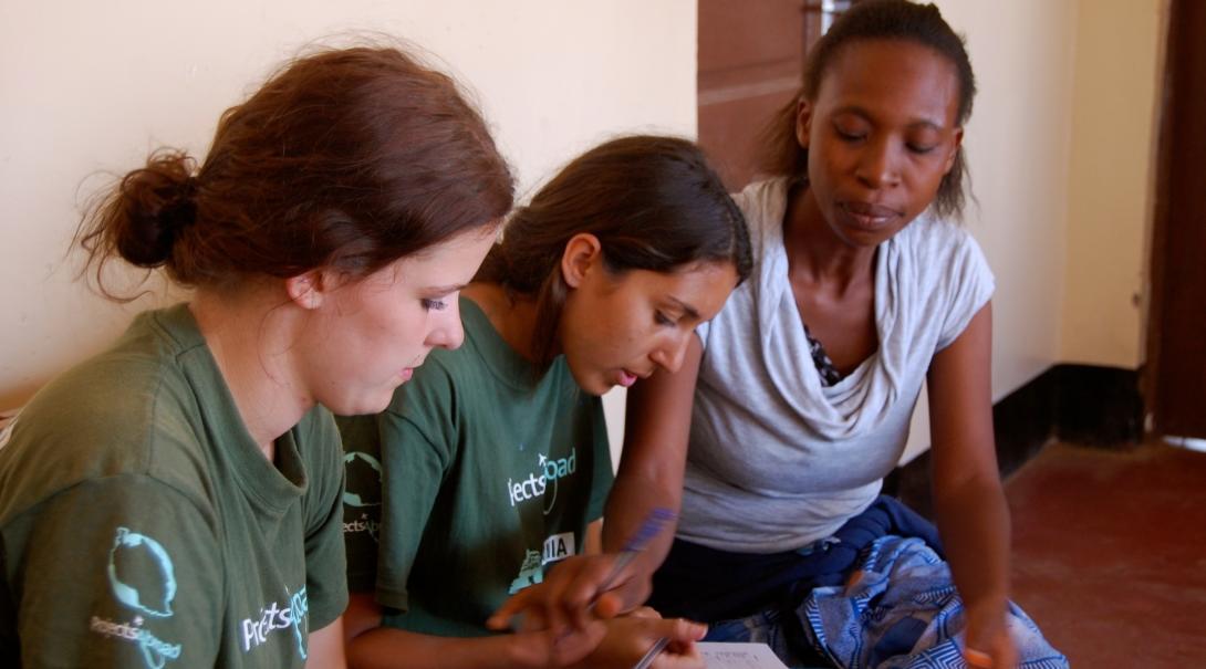 Interns with Projects Abroad helping a local lady fill out a medical note during their time on a occupational therpay internship in Tanzania.