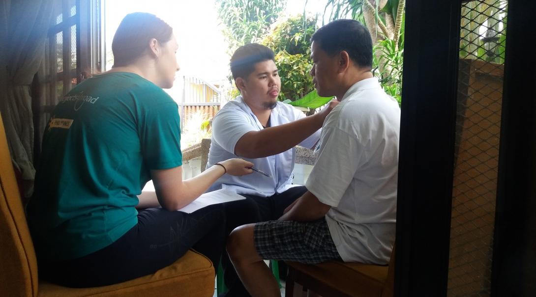 A Projects Abroad intern assisting with the treatment of mans shoulder pain during her physiotherapy internship in the Phillippines.