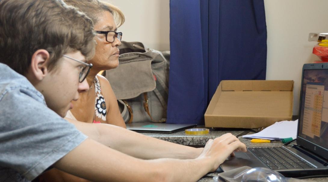 A local woman learns computer skills from a young volunteer doing a teaching IT placement in South Africa. 