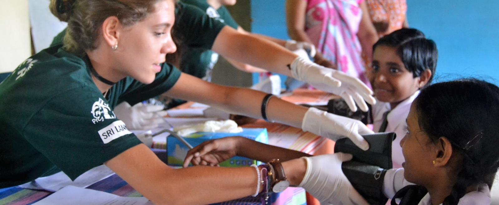 A young girl has her blood pressure taken on Projects Abroad's medical internship for high school students in Sri Lanka