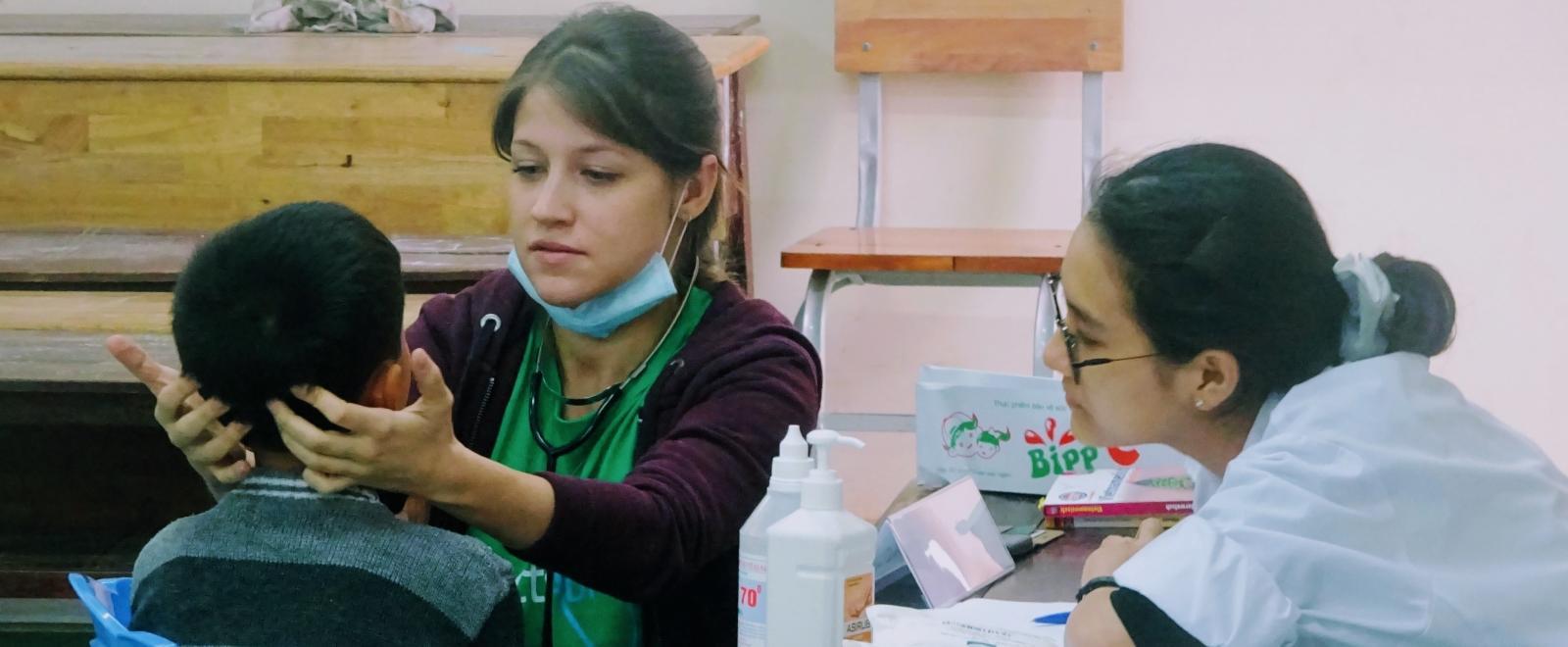 A local child gets a medical check during an outreach from an intern doing her Nursing internship in Vietnam.