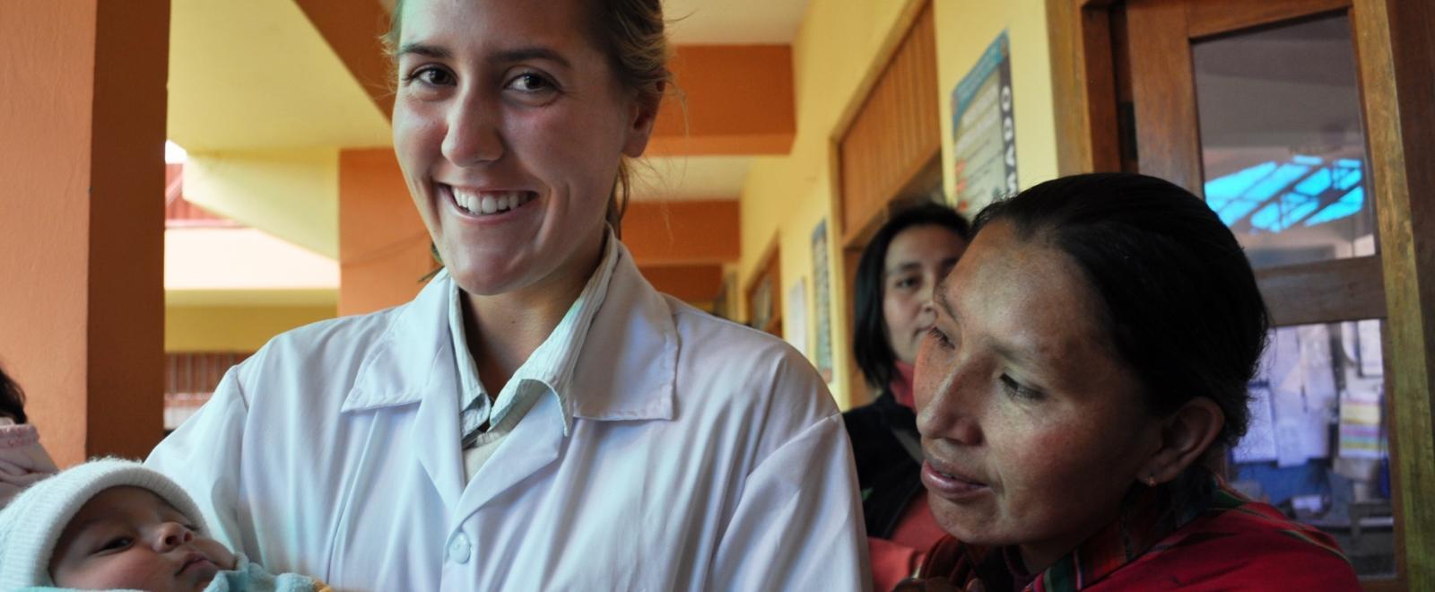 A student doing her Midwifery internship abroad holds a new-born infant at a local hospital.