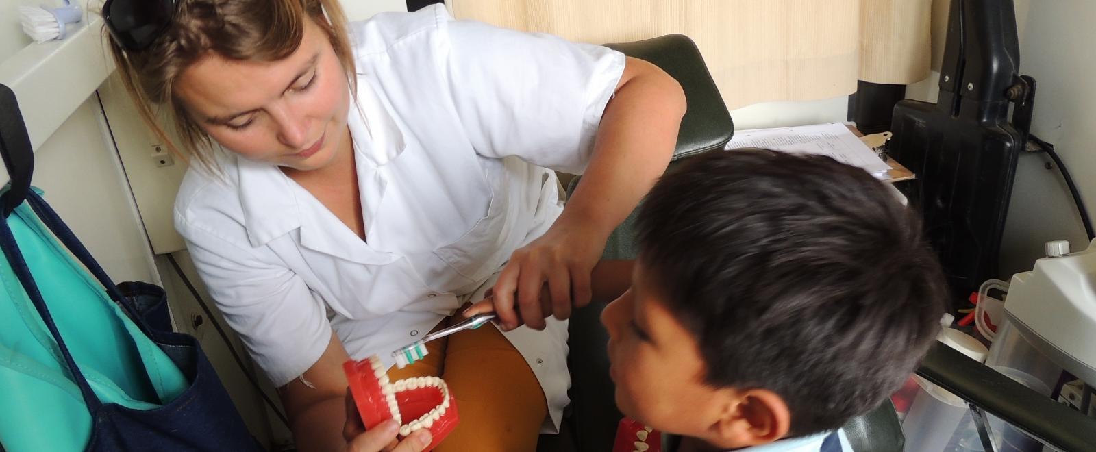 A young boy learns how to brush his teeth correctly with the help of a student doing a Dentistry internship abroad.