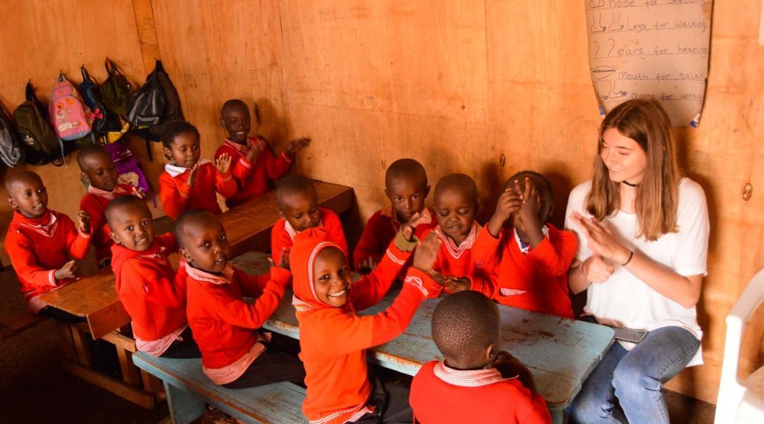 A volunteer assists with volunteer work with children for teenagers in Kenya while singing songs and having fun with her students.