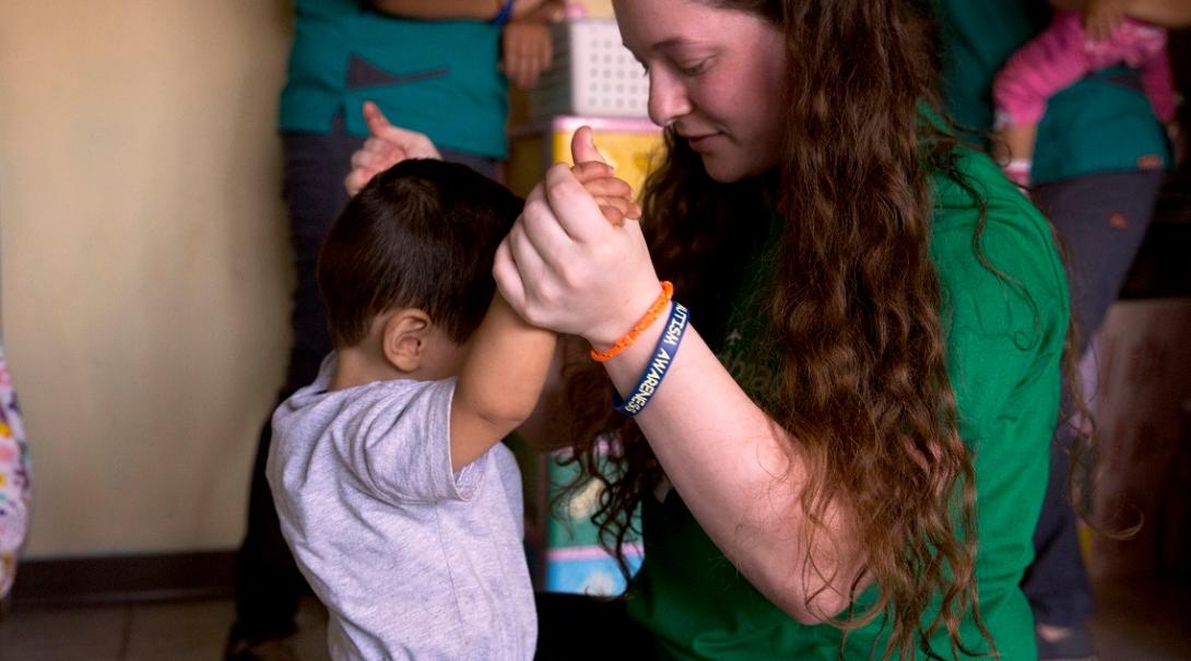 A Projects Abroad volunteer with children in Costa Rica, helps a young boy with his balance