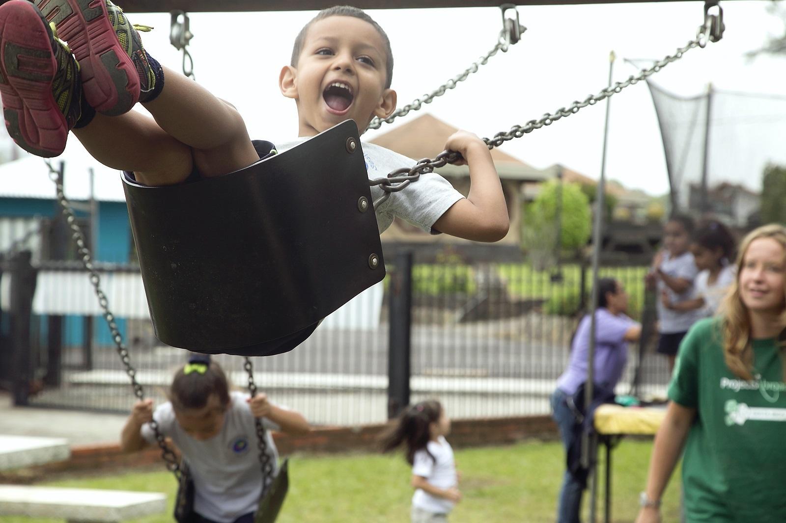 Children play on the swings under the supervision of a volunteer working with children in Costa Rica