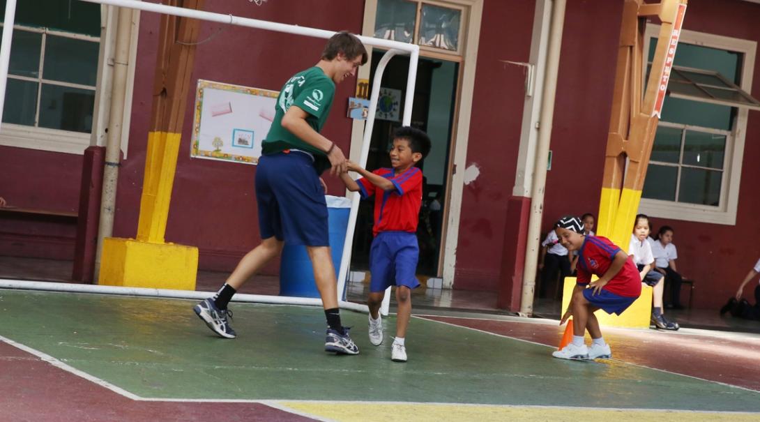 A volunteer runs with a kid during practice on the sport volunteering project in Costa Rica