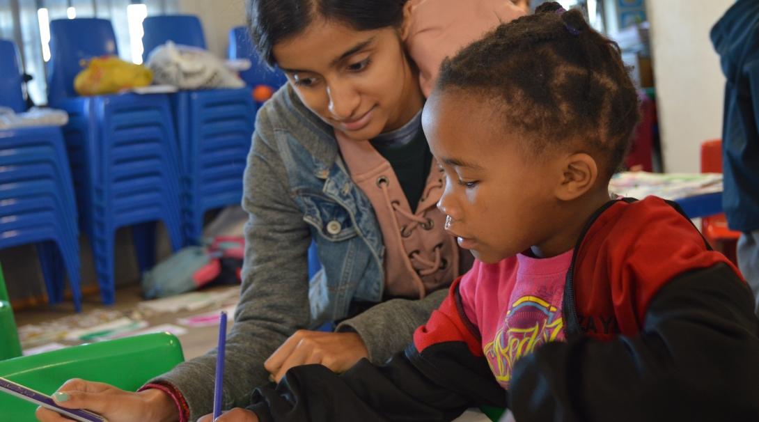 A teenager helps a child with a literacy exercise on one of our best high school volunteer abroad programs.