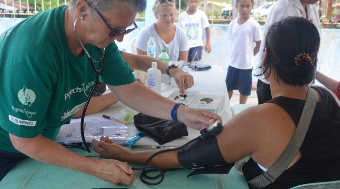 Healthcare volunteer measures the blood pressure of a local as part of her voluntary work for pensioners