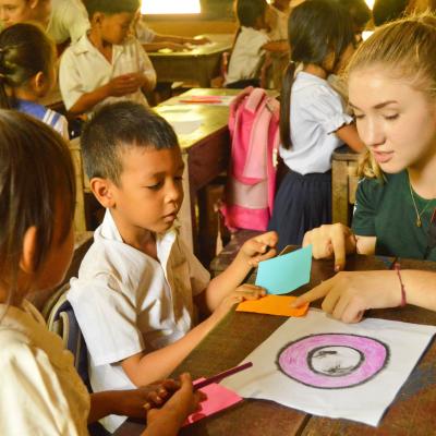 Childcare volunteer teaches a young boy different colours during school in Cambodia