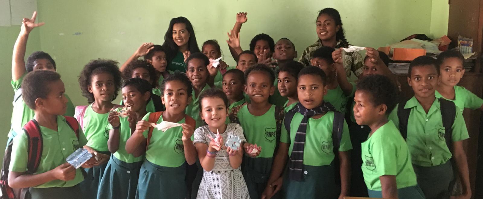 A mother and her daughter take a group photo with the students they worked with in Fiji