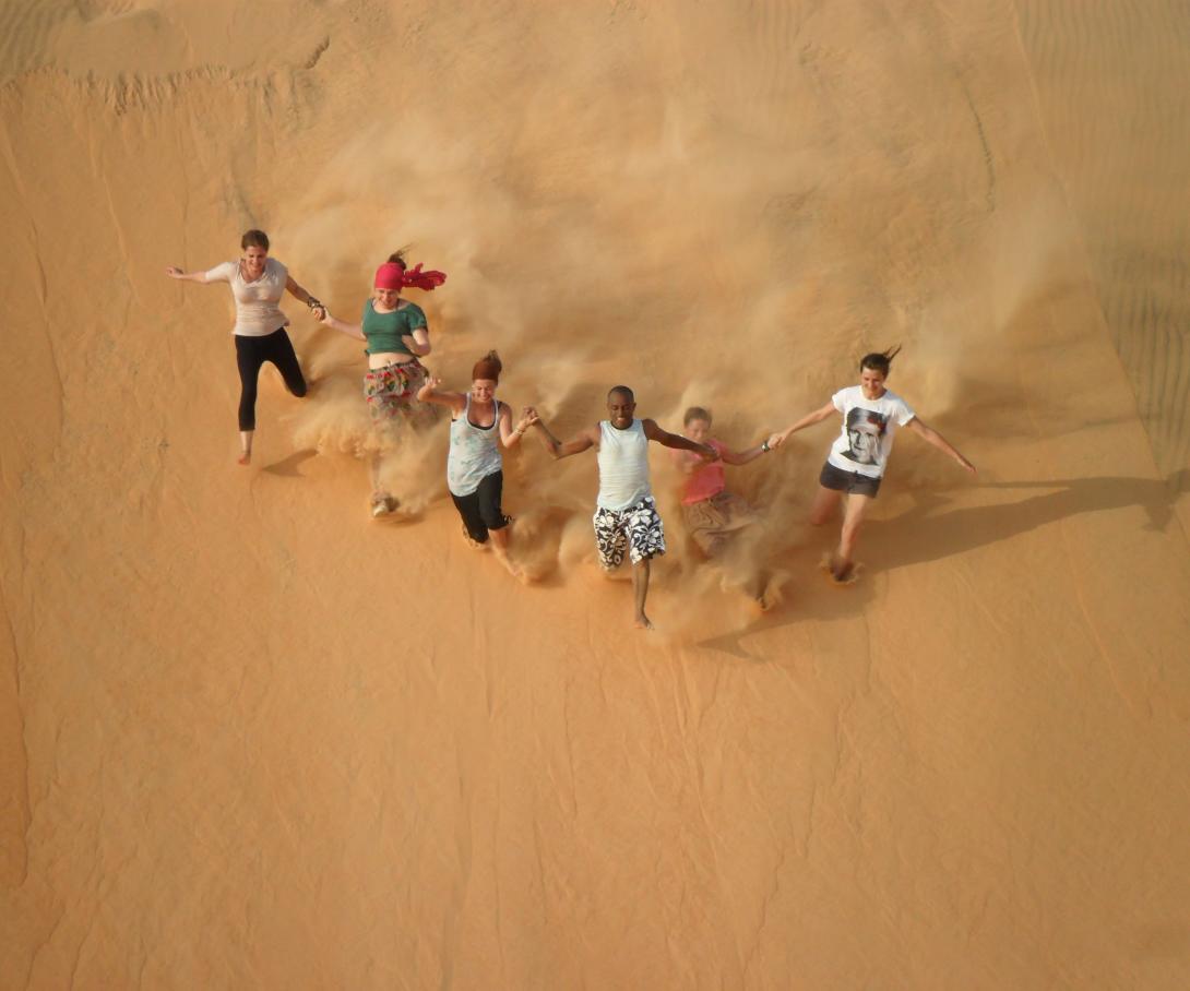 Projects Abroad volunteers run down a sand dune as part of their gap year activities in Senegal.