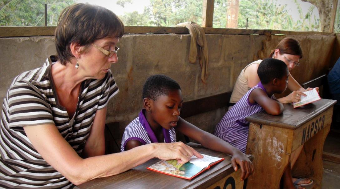 A couple of volunteers doing a teaching English project in Ghana with Projects Abroad participate in a reading club.