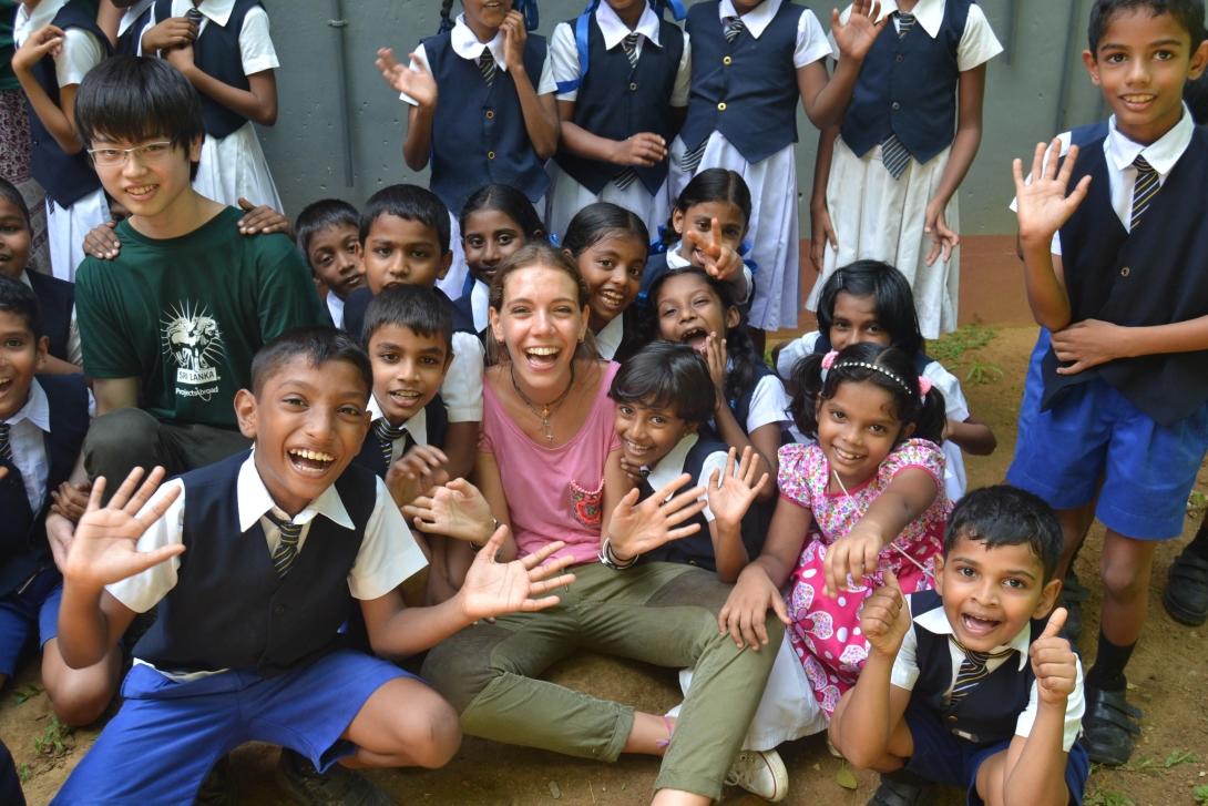 Female volunteer and children getting excited during a group photo.