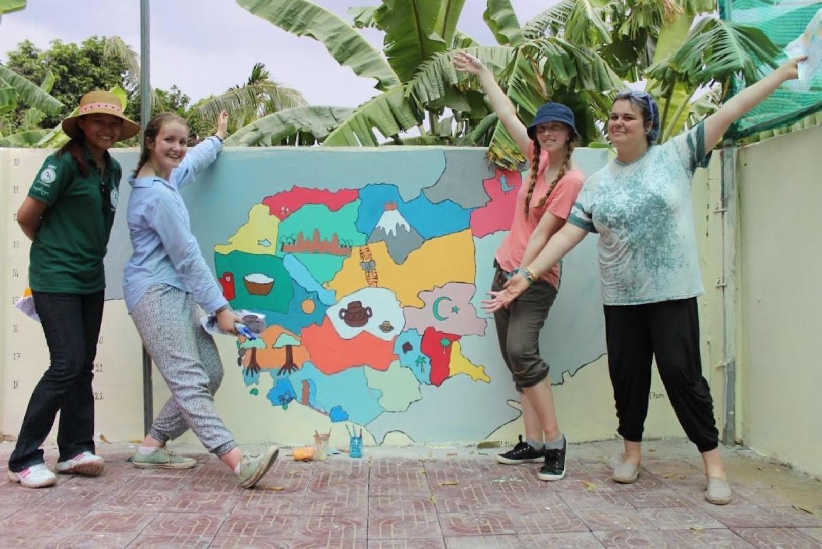 Volunteers showing their painting on a Kindergarten wall in Cambodia