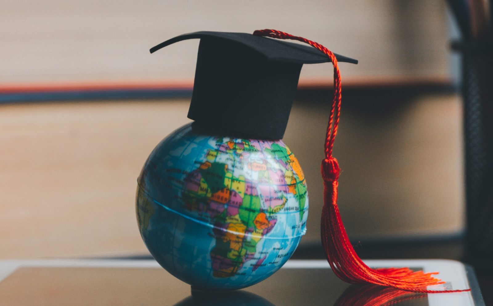 Globe with a mortar board on on top of an open book